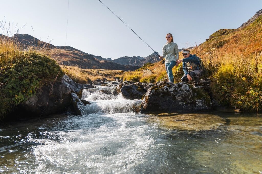 Image du guide de d'une cliente en train de pêche la truite dans un ruisseau de montagne en Savoie. 